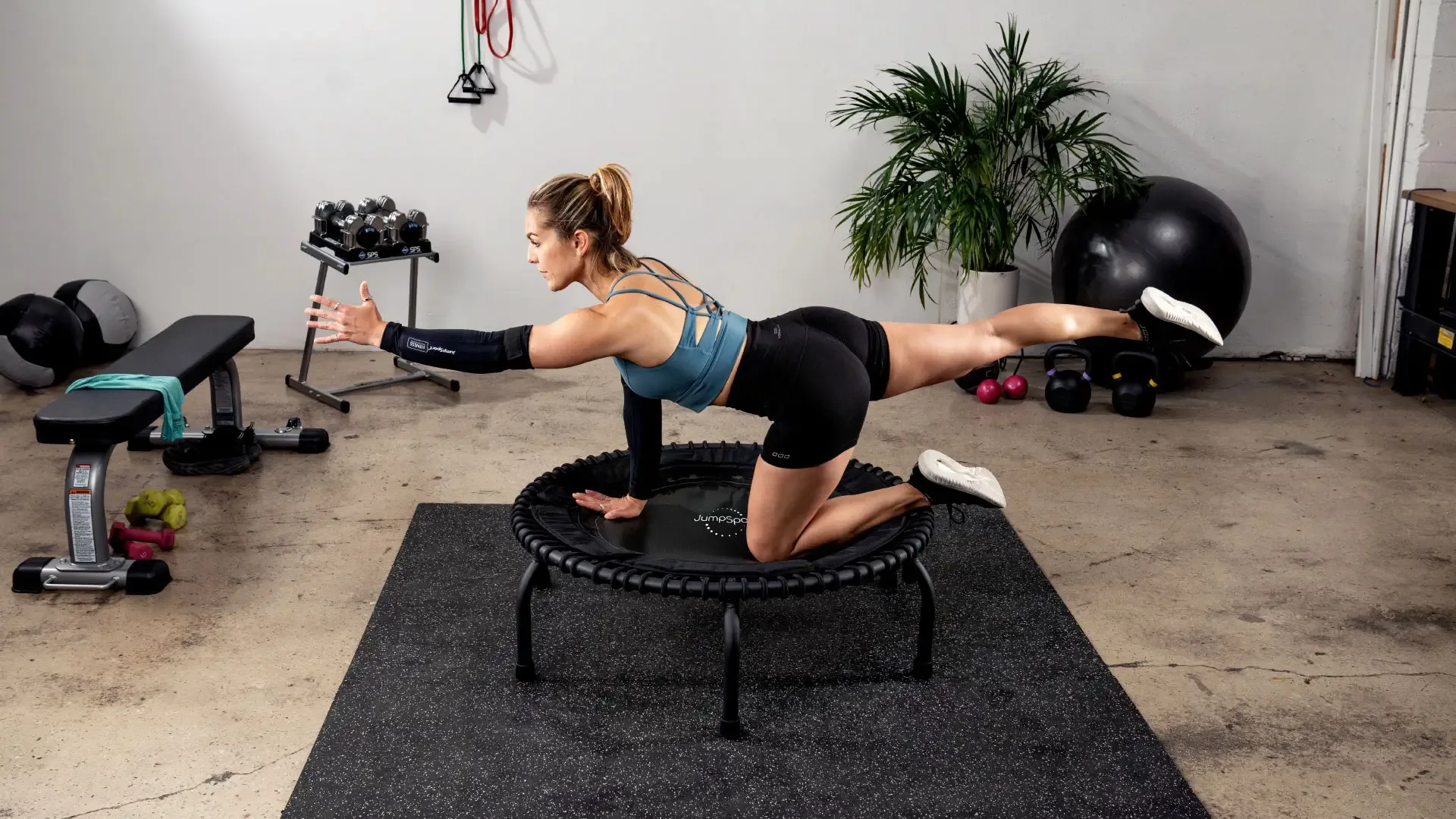 JumpSport fitness trampoline in gebruik, met trainingsaccessoires op de achtergrond.