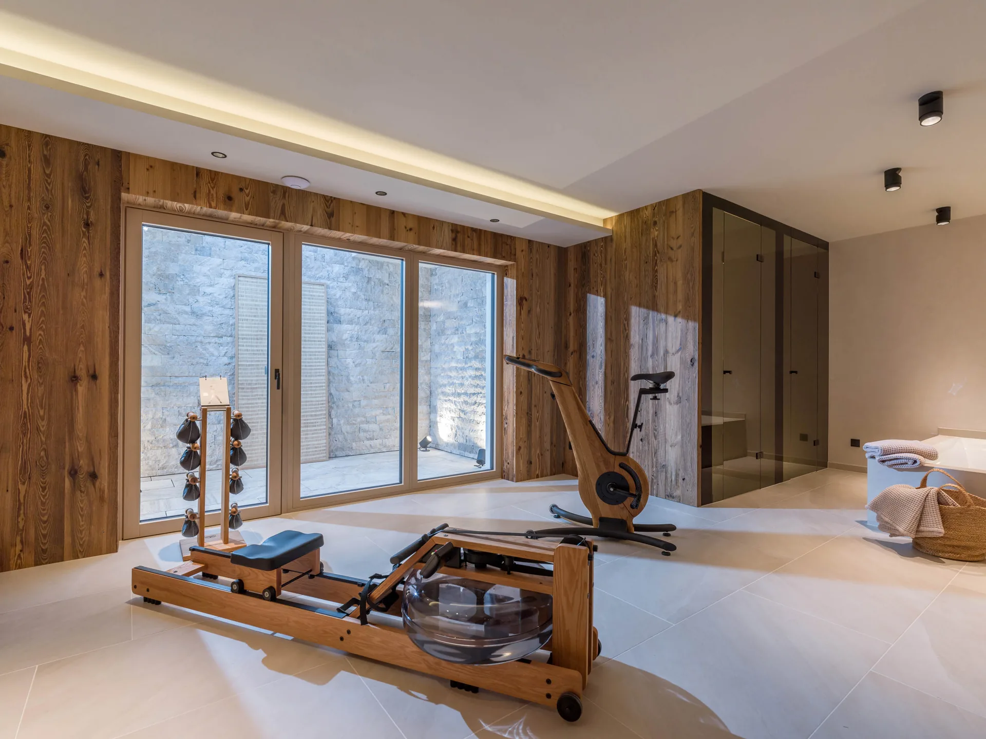 WaterRower en NOHRD-bike naast een spa-achtige badkamer.